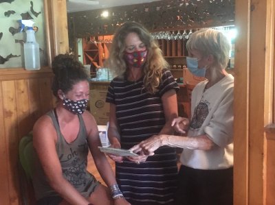 Daphne Bennink (center) reviews new items with employees Beatle Haddad and Tricia Palmisano. 