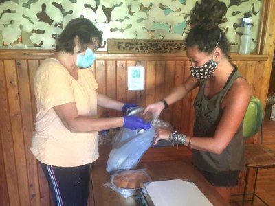 Local Business Evolves for 2020 Beatle Haddad helps local resident Trudy Austin bag up her purchases.